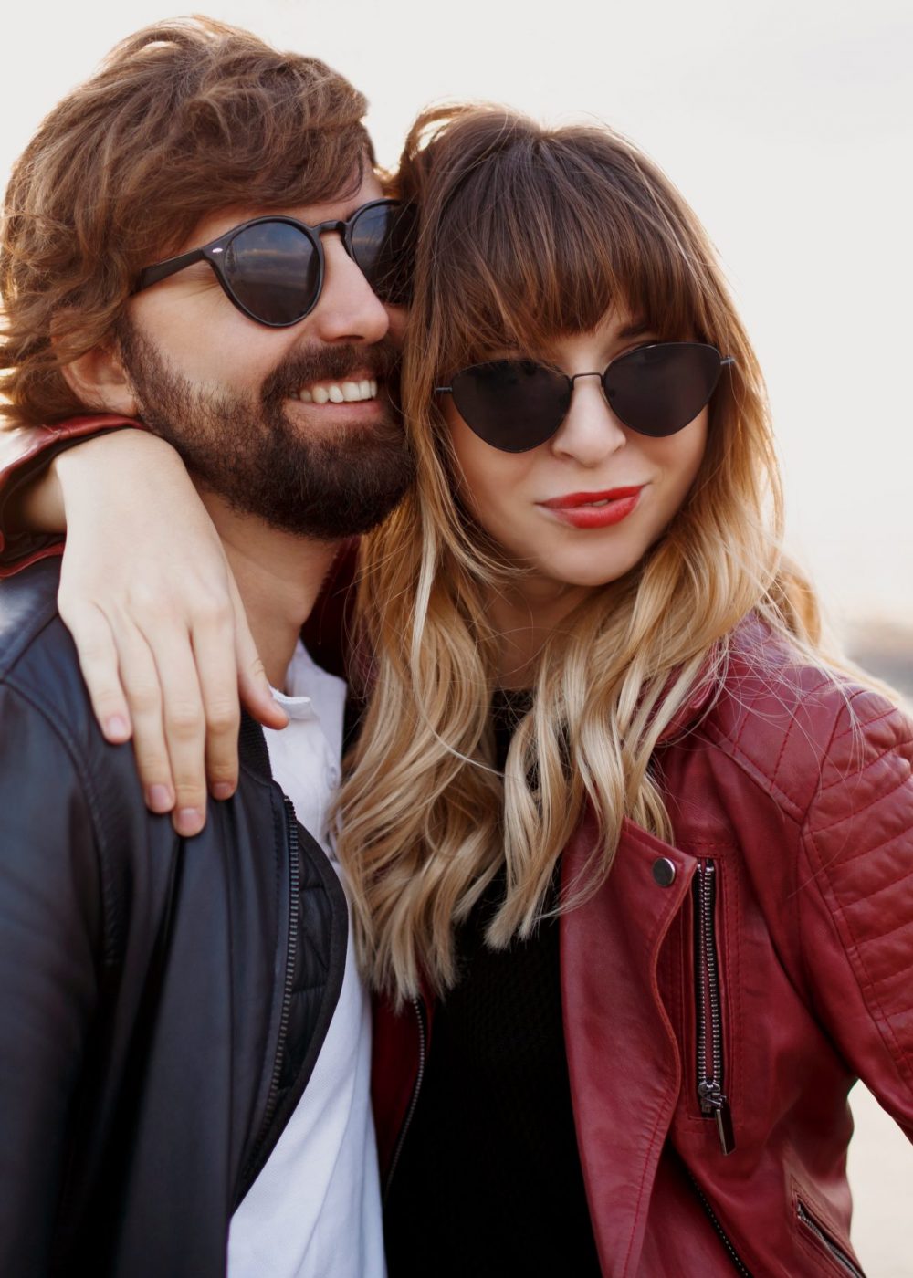 Attractive stylish couple in love posing outdoor, hugging and walking on quay. Soft evening colors. Fashionable look. Trendy sunglasses. Man and woman embarrassing.